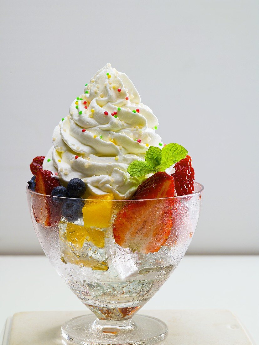 Mixed fruit on ice cubes with whipped cream