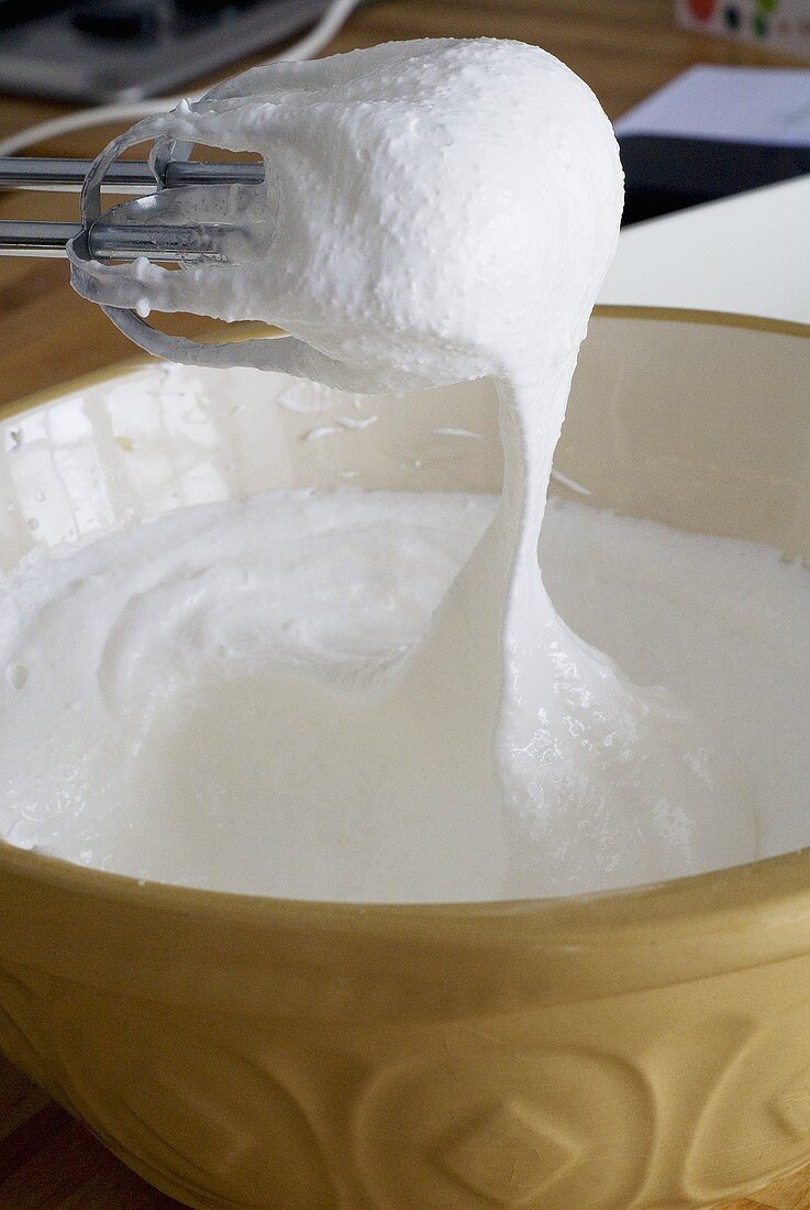 Meringue mixture in a bowl with whisk