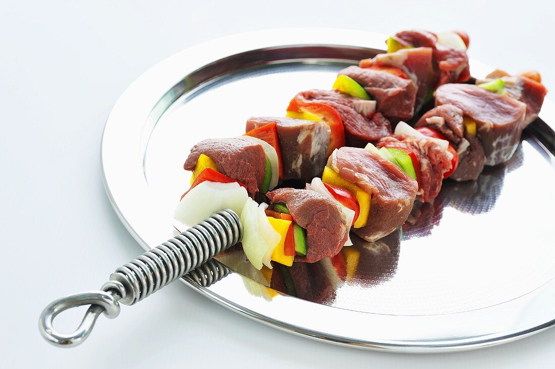 Two raw meat and vegetable kebabs