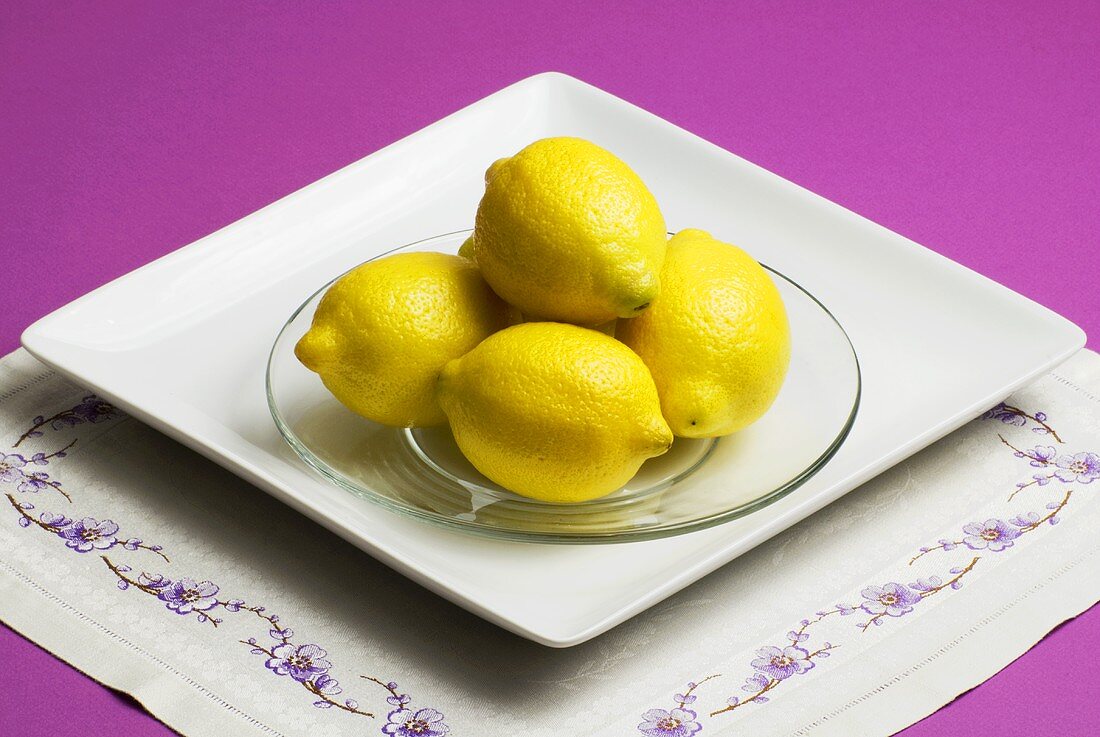 Fünf Zitronen auf Glasteller