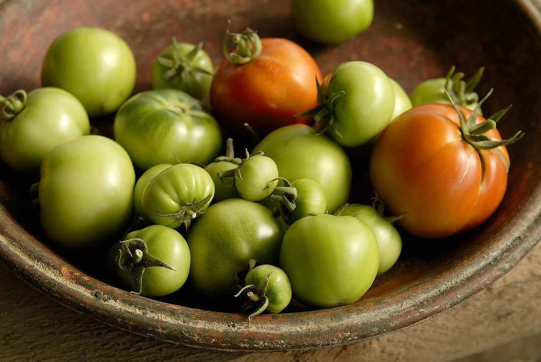 Green and red tomatoes in terracotta dish