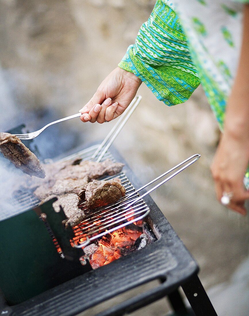Frau grillt Fleisch im Freien