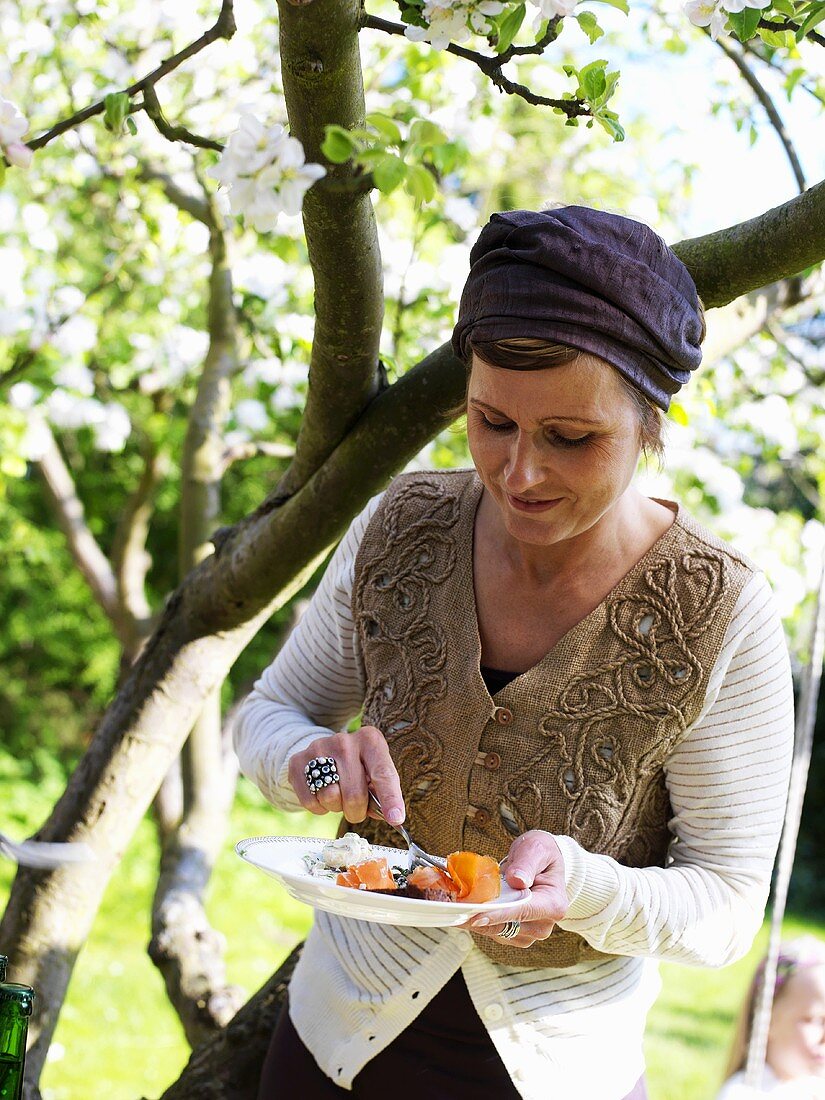 Frau isst Lachs beim Smorgasbord-Buffet im Garten (Schweden)