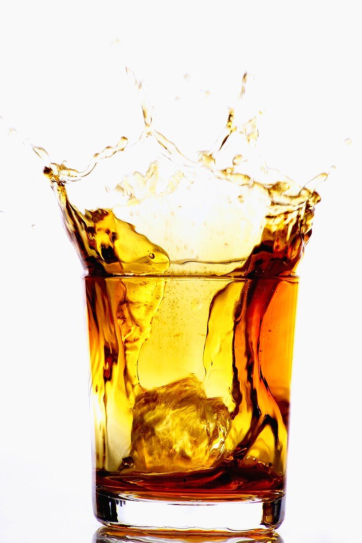 Ice cube falling into whisky glass – License Images – 11039807 ❘ StockFood