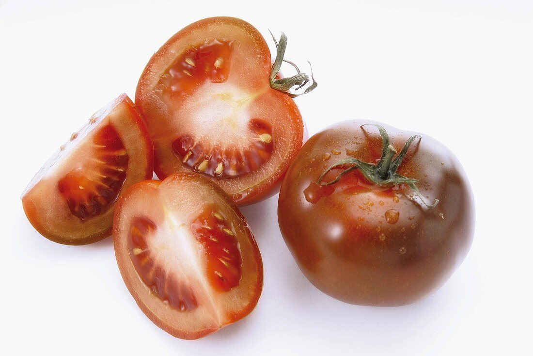 Tomaten (Sorte Kumato), ganz, halbiert und Viertel