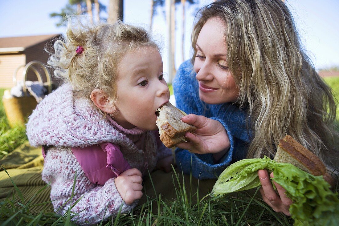 Mutter und Tochter essen belegte Brote im Freien