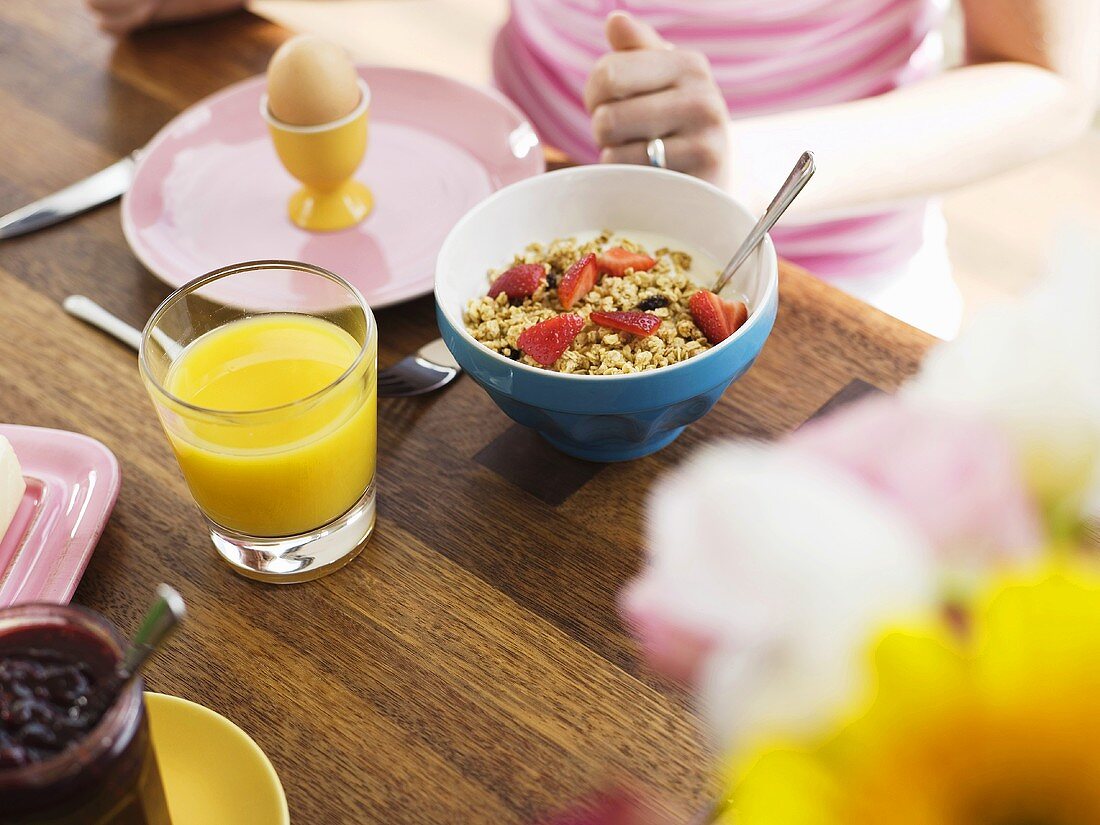 Frühstückstisch mit Orangensaft, Müsli und Ei