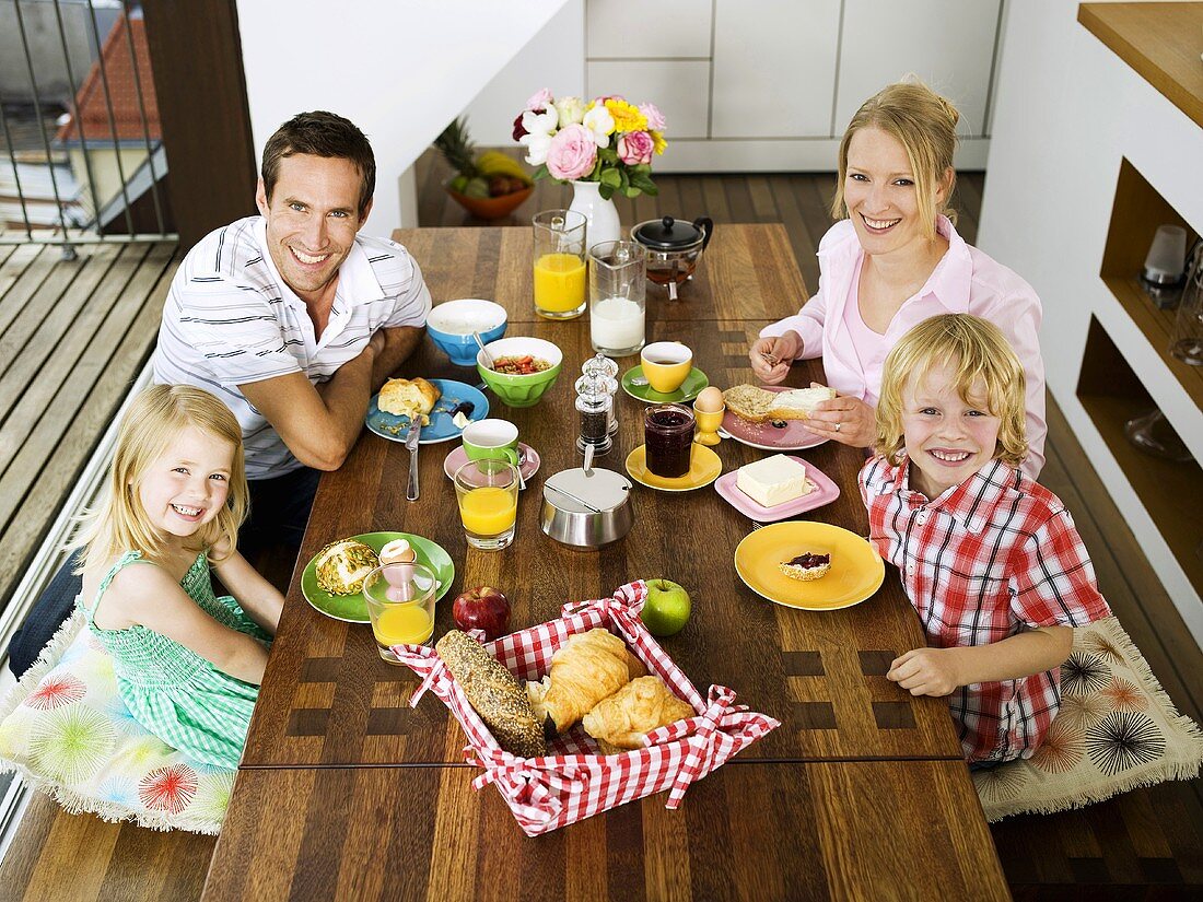 Familie mit zwei Kindern sitzt am Frühstückstisch