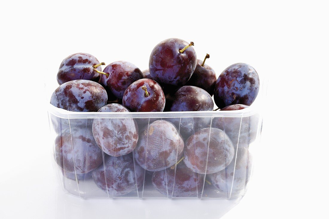 Fresh plums in plastic container