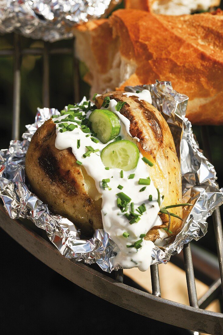 Baked potato with chive sauce on barbecue
