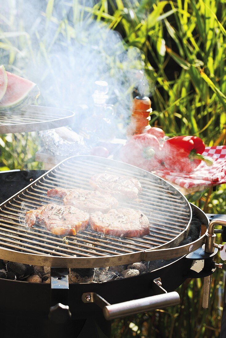 Pork steaks on smoking barbecue out of doors