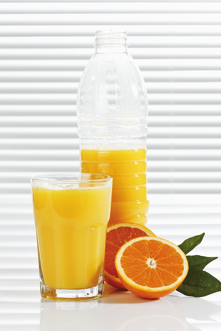 Orangensaft in Glas und Plastikflasche