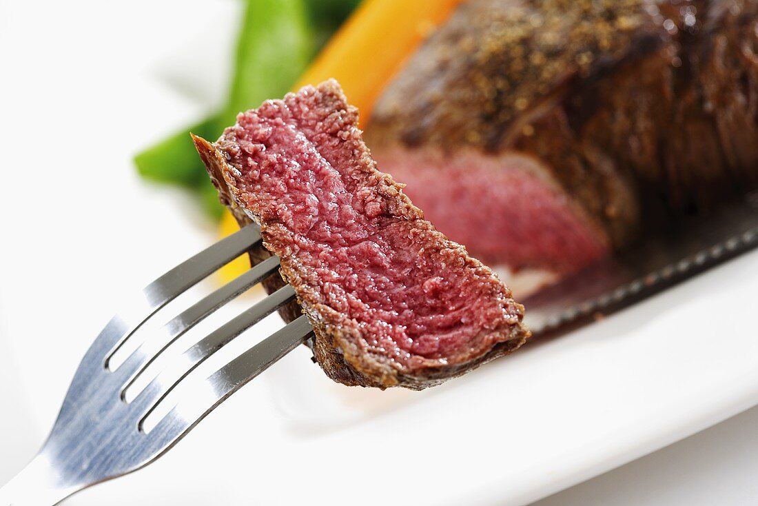 Piece of fried fillet steak on fork