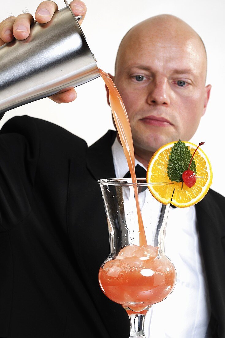 Barkeeper pouring cocktail into glass, close-up