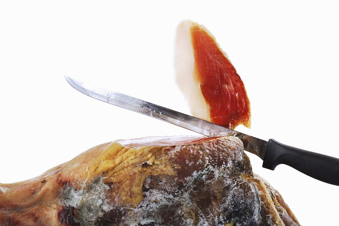 Cutting a slice from a whole Serrano ham