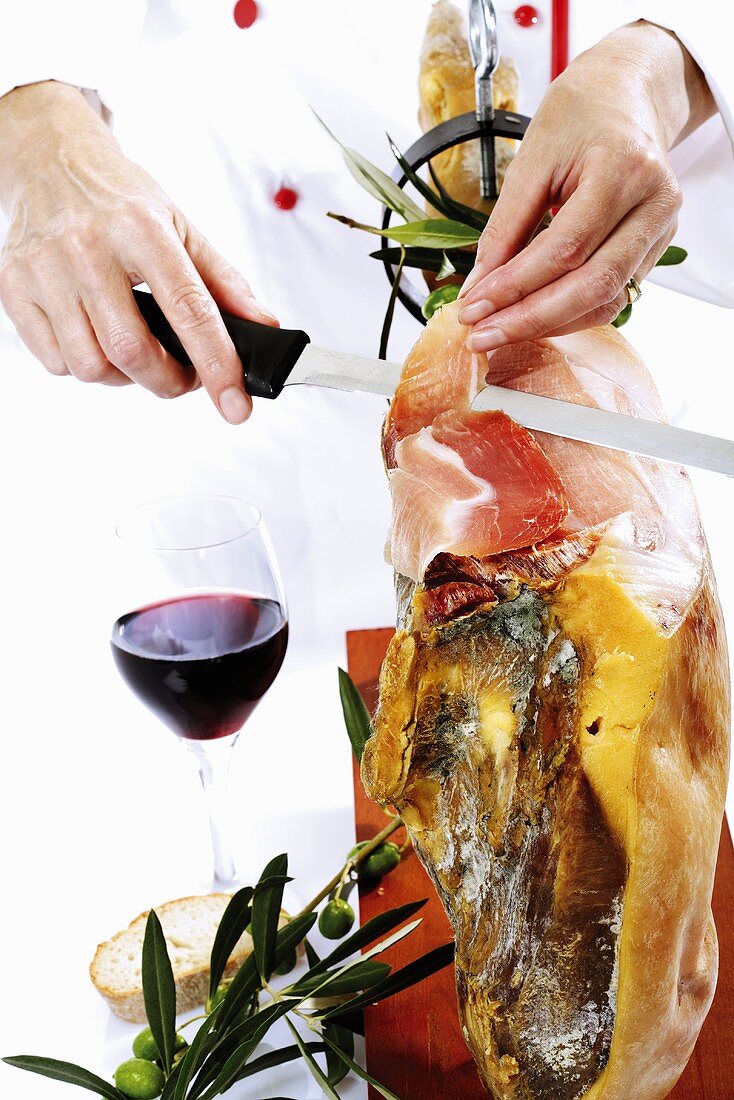 Chef cutting Serrano ham, close-up, mid section