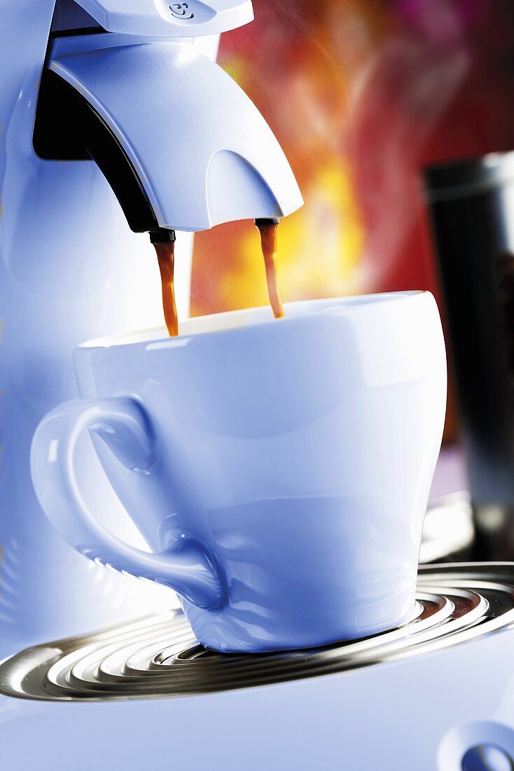 Espresso fliesst aus Kaffeemaschine in Tasse