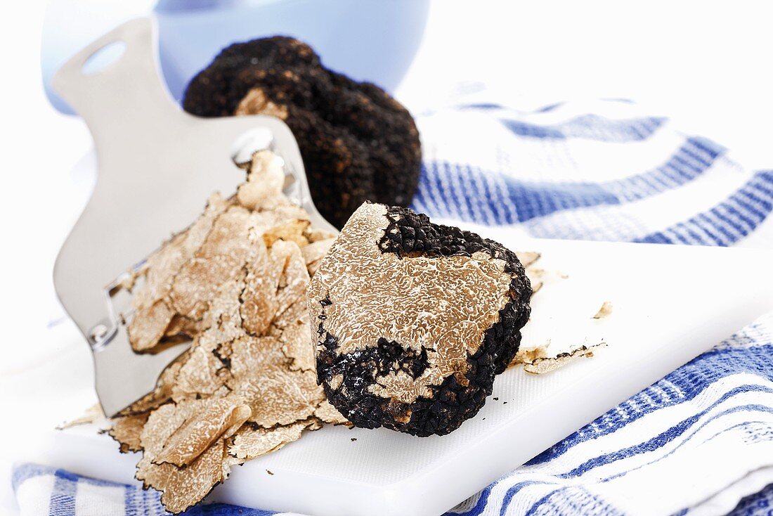 Black truffle with truffle slicer on chopping board