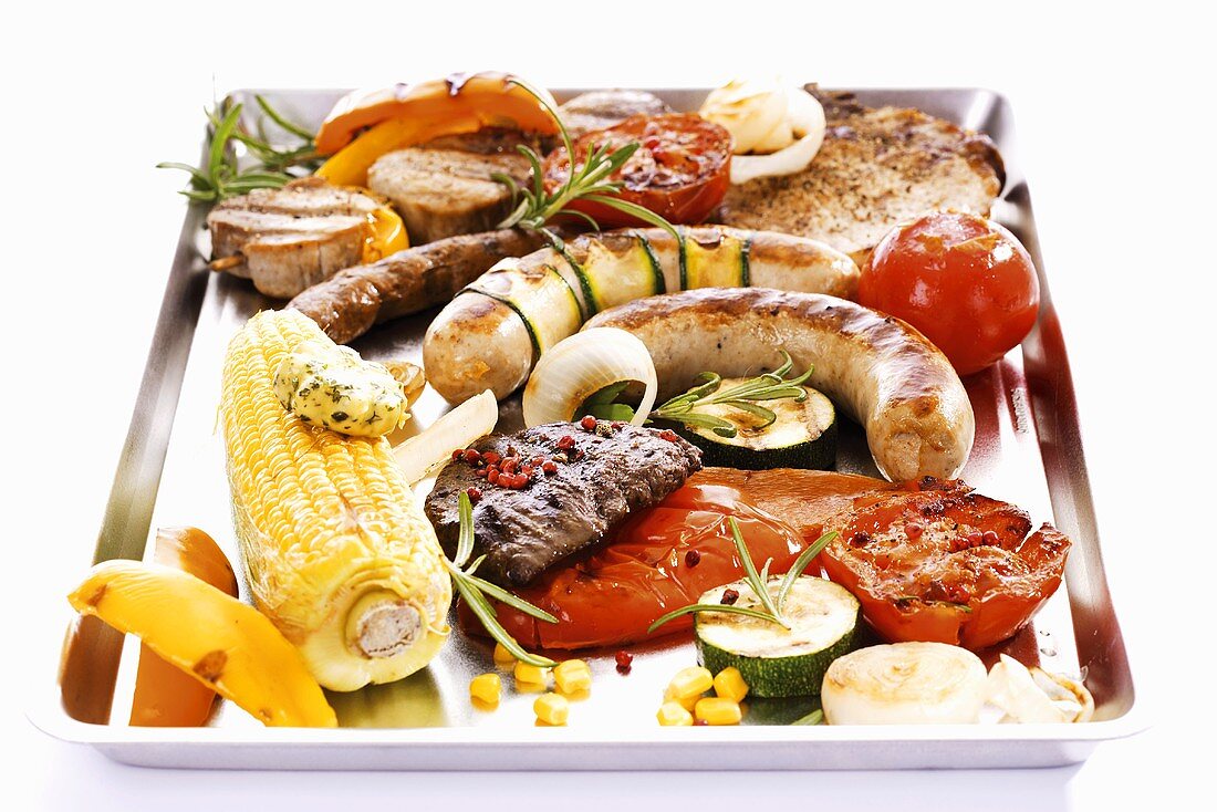 Grillplatte mit Fleisch, Wurst, Gemüse und Maiskolben