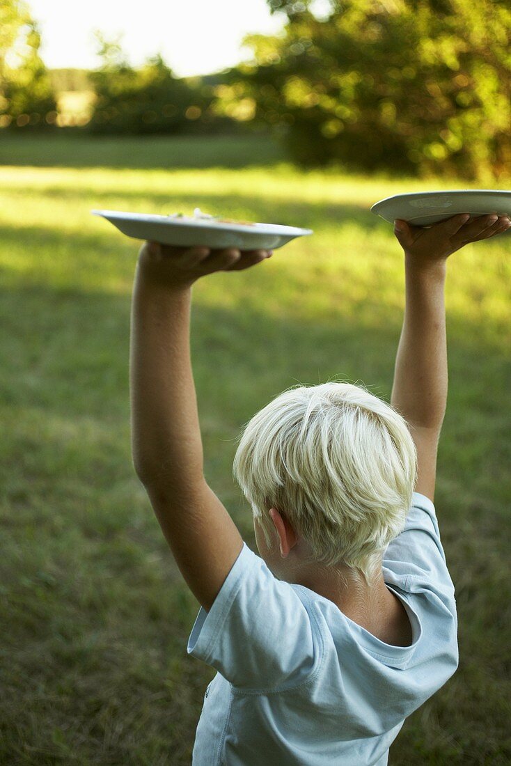 Blond boy carrying two plates