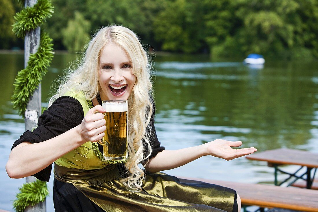 Blonde Frau mit einem Krug Bier im Biergarten
