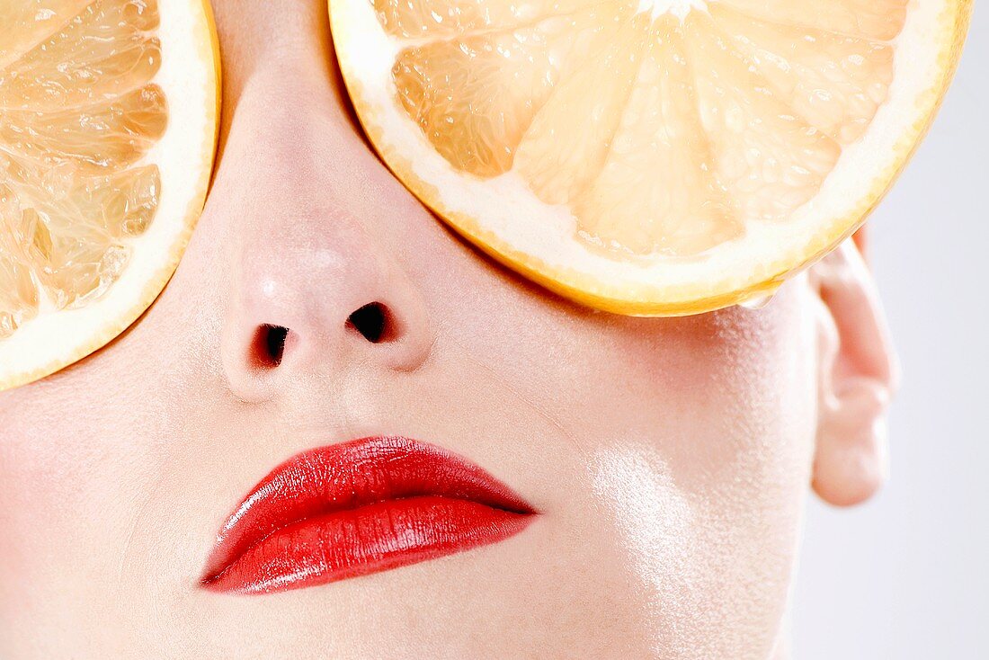 Woman, eyes covered with orange slices, close-up