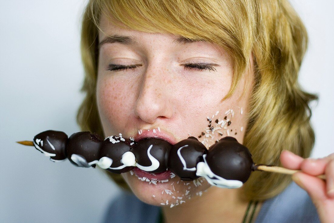 Woman eating chocolate fruit spit, closed eyes
