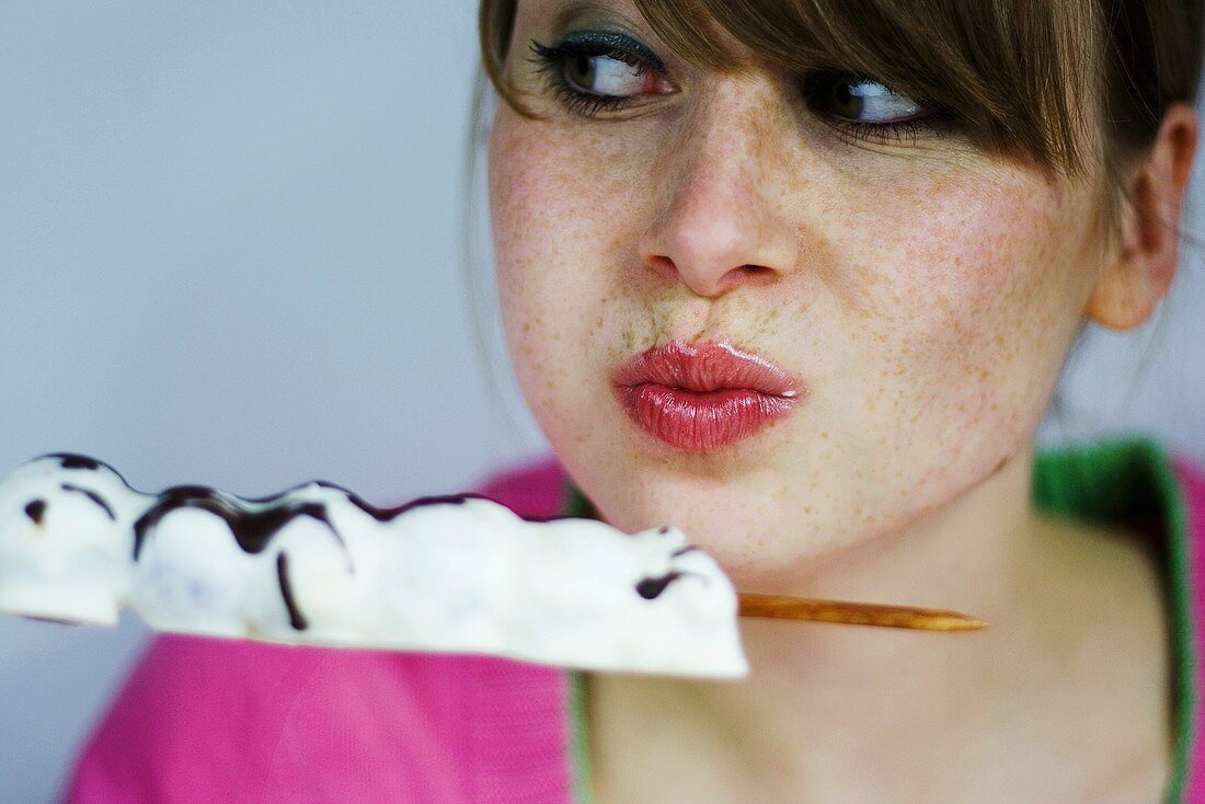 Young woman eating chocolate sweet