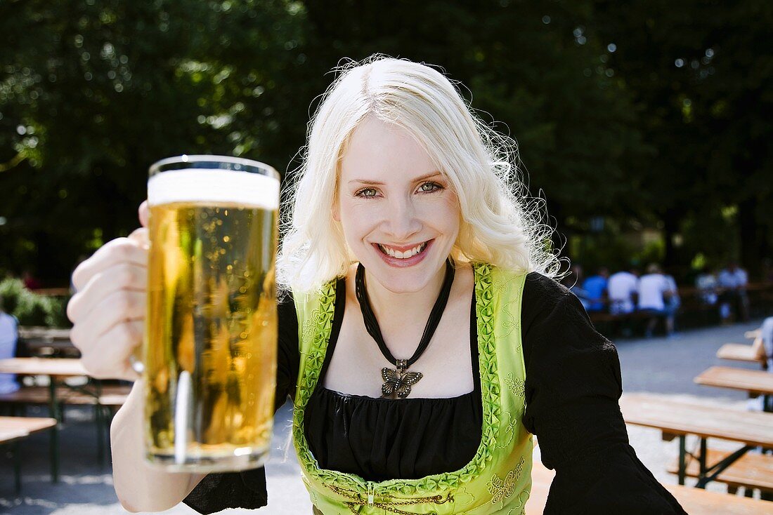 Blonde Frau mit einem Krug Bier im Biergarten