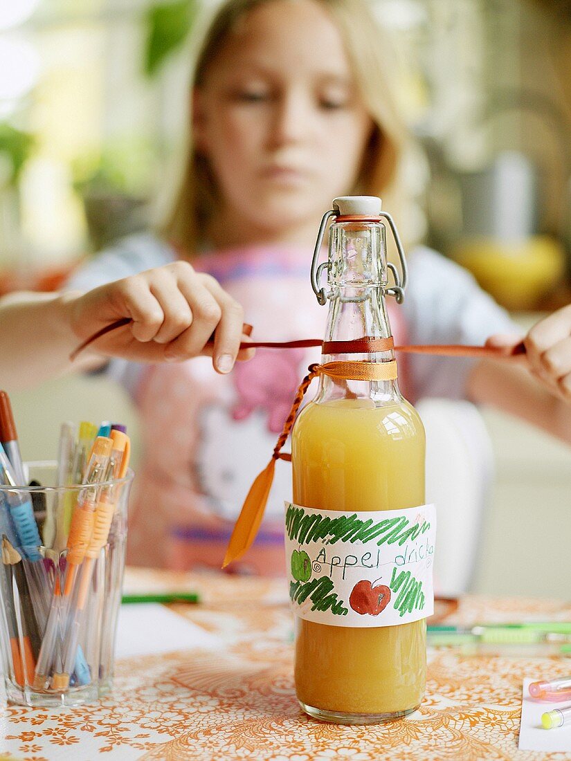 Mädchen dekoriert eine Flasche mit Apfelsaft