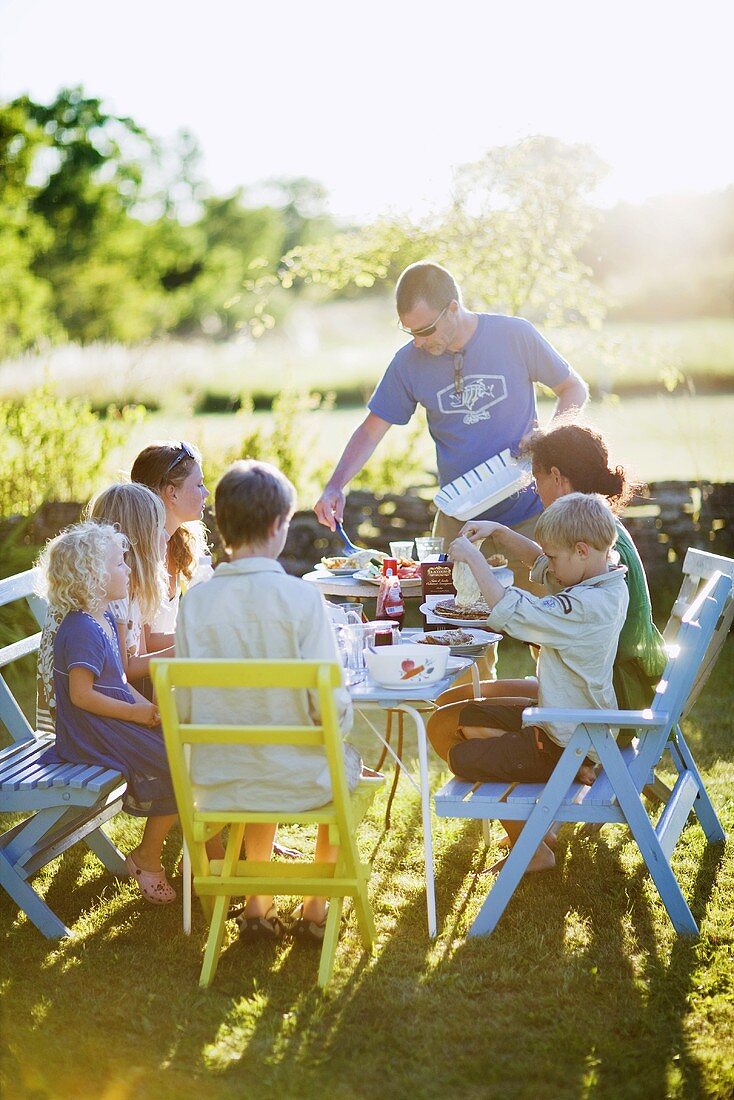 Familie mit mehreren Kindern isst im Garten