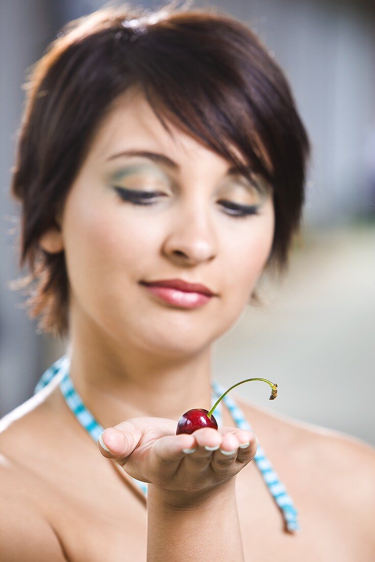 Young woman with a cherry on her hand