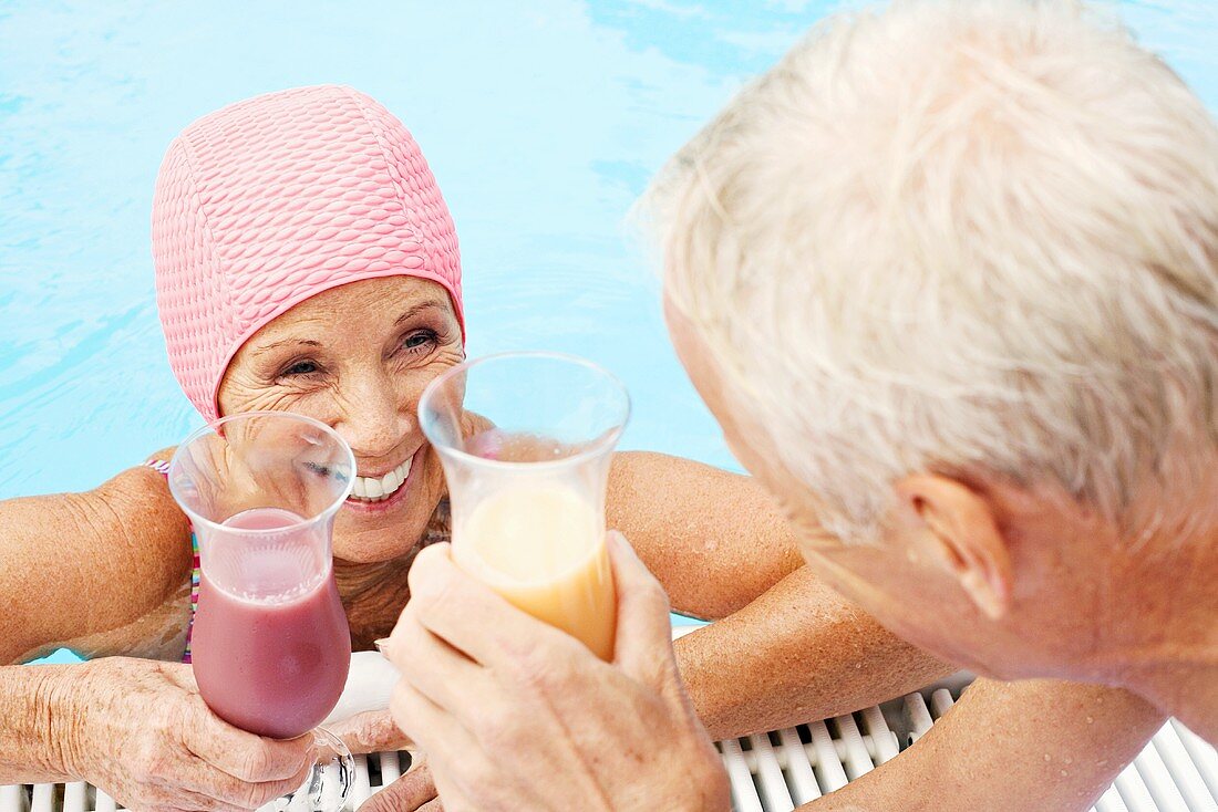 Älteres Paar mit Cocktails am Swimmingpool