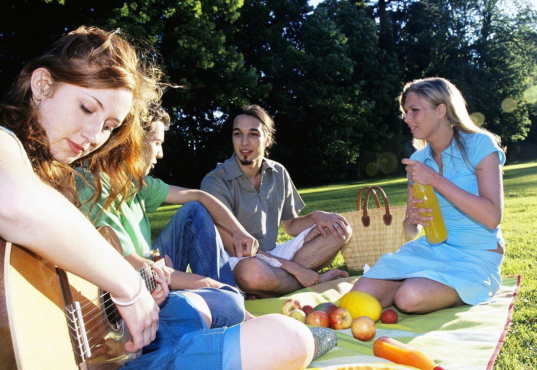 Junge Frau spielt Gitarre beim Picknick