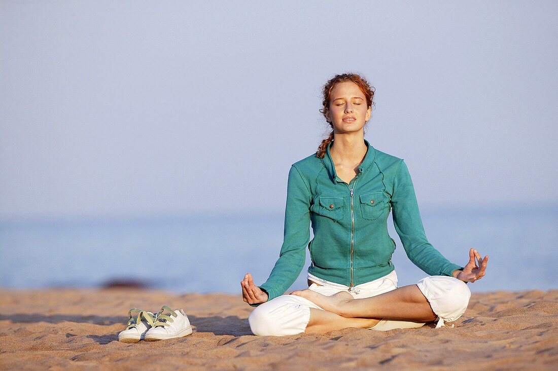 Young woman meditating on beach