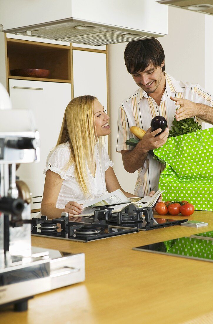 Young couple in kitchen, man holding vegetable