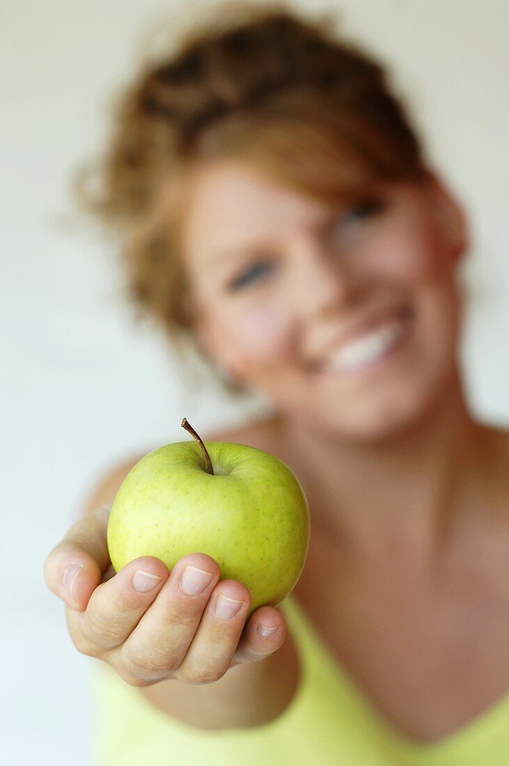 Frau hält Apfel in ausgestreckter Hand