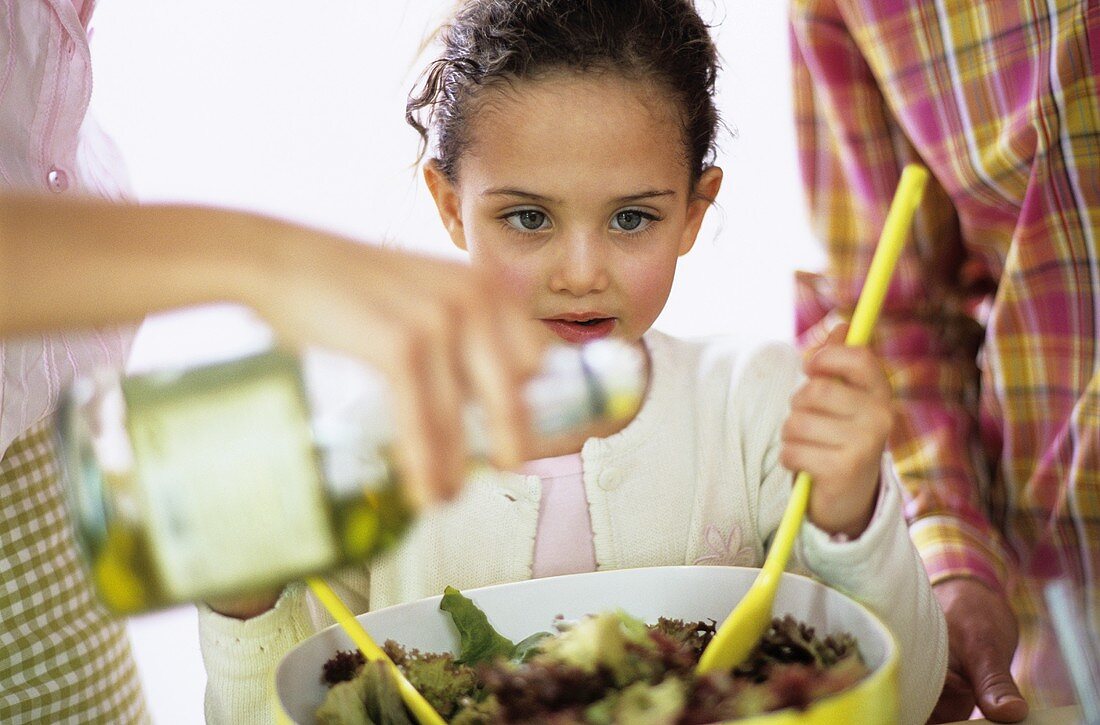 Eltern und kleine Tochter bereiten Blattsalat zu