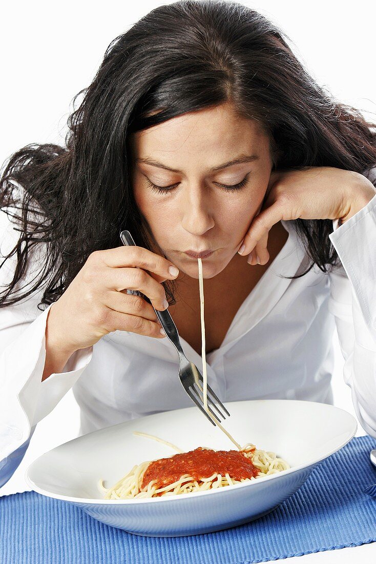 Young woman eating spaghetti with fork, portrait