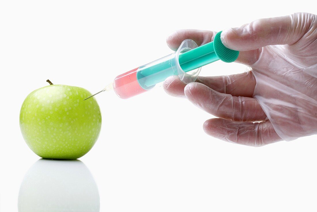 Hand sticht Spritze in Apfel