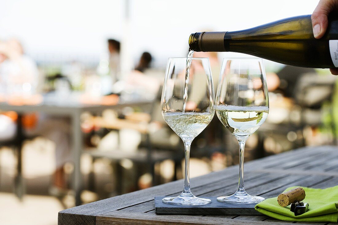 Weißwein auf der Terrasse eines Restaurants einschenken