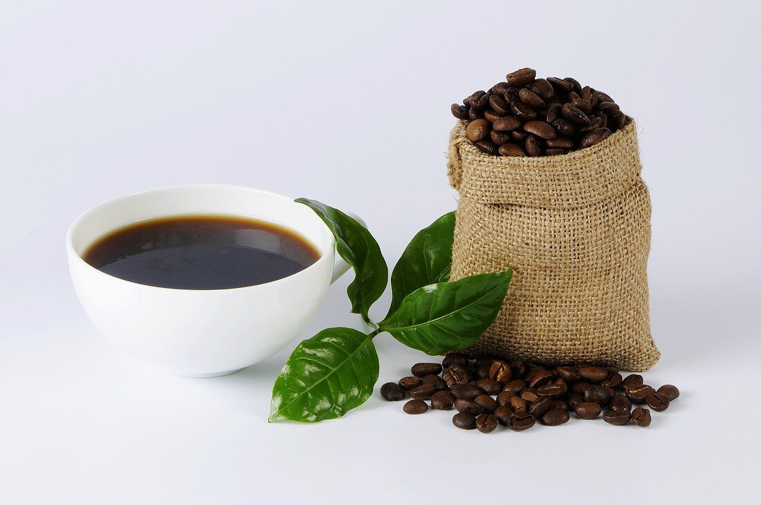 Cup of coffee with a small sack of coffee beans