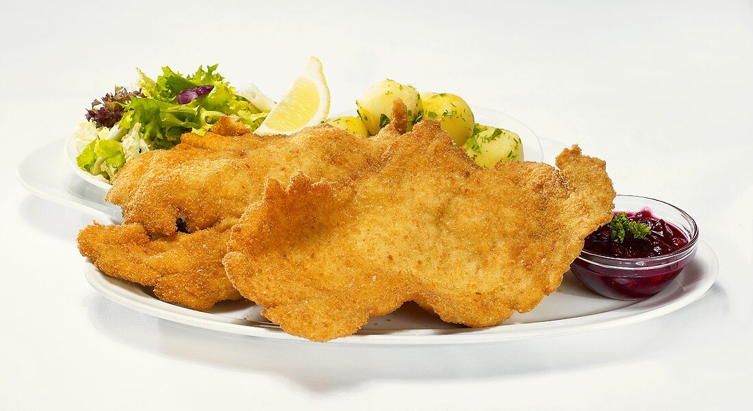Wiener schnitzel with cranberries, parsley potatoes and salad leaves