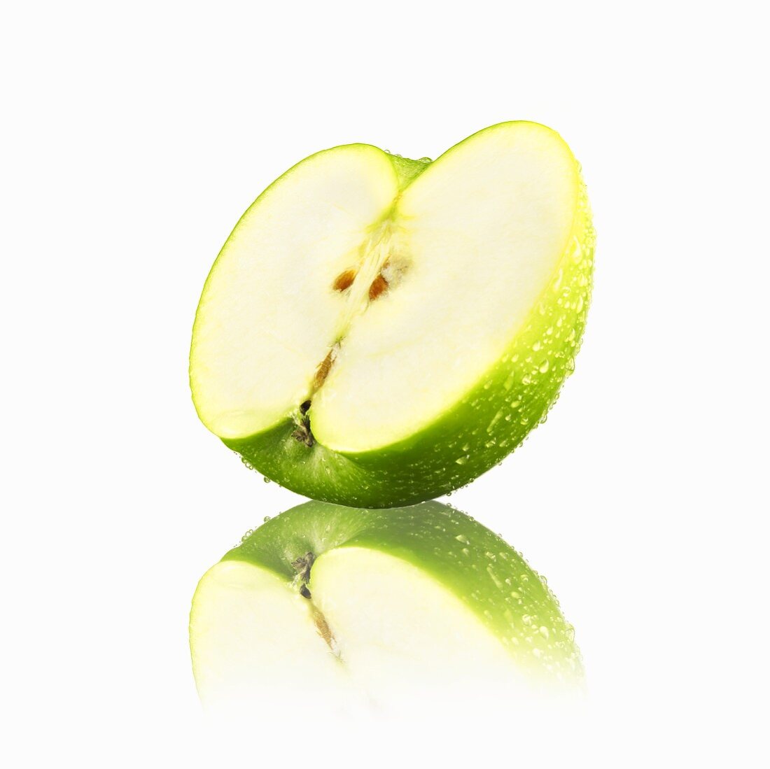 Half a green apple with drops of water and reflection
