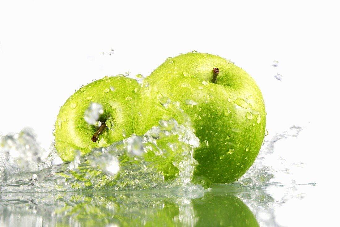 Two green apples with splashing water