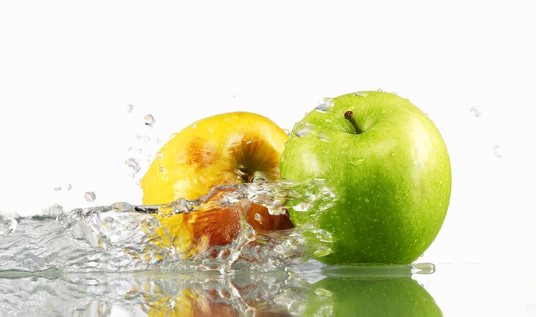 One green and one yellow apple with splashing water