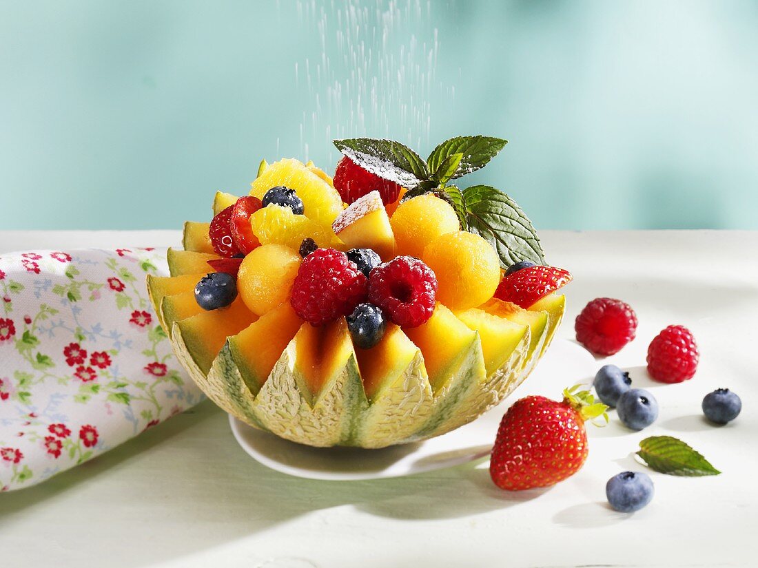 Sprinkling fruit-filled melon with icing sugar