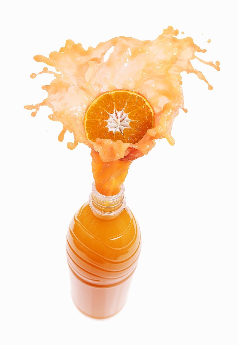 Mandarin orange juice splashing out of bottle