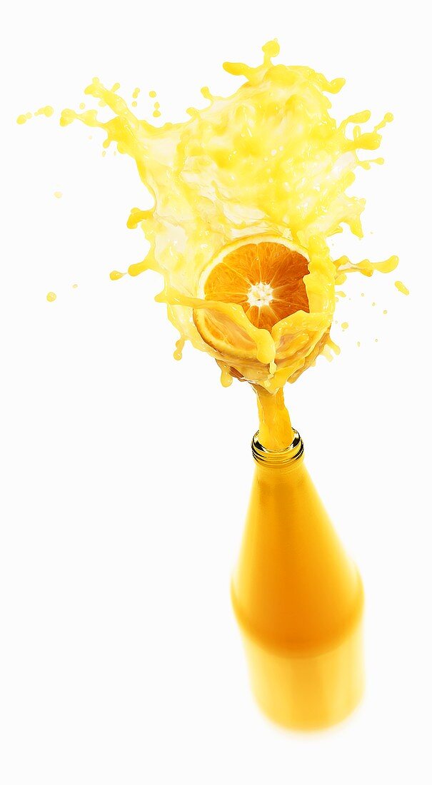 Orange juice splashing out of bottle