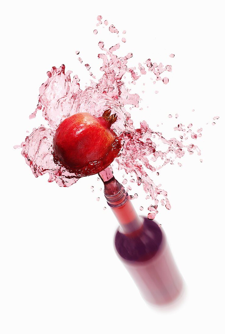Pomegranate juice splashing out of bottle